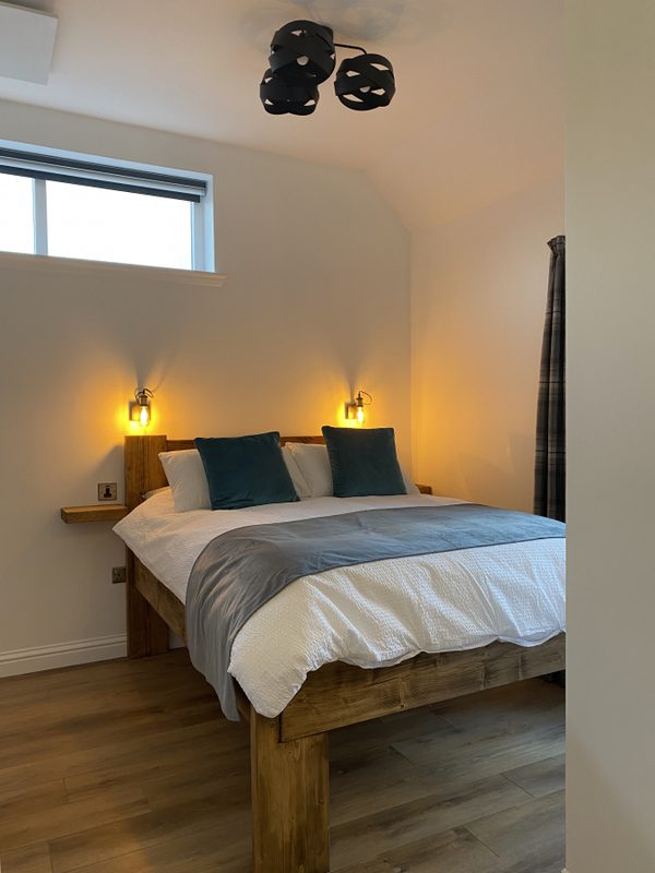 Bedroom from the foot of the bed, with warm reading lamps lit either side